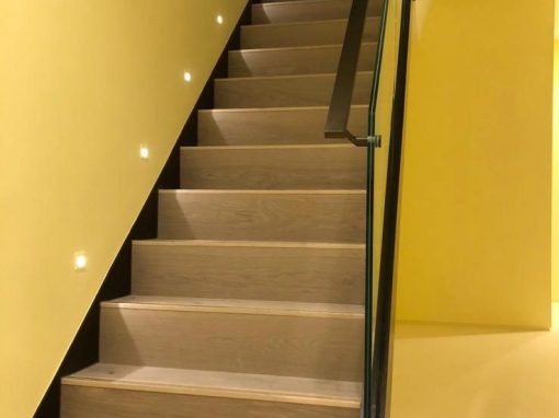 Modern staircase upgrade with engineered wood steps, glass balustrade, and subtle LED lighting