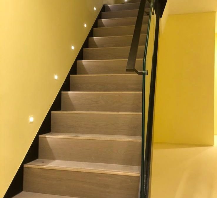 Modern staircase upgrade with engineered wood steps, glass balustrade, and subtle LED lighting